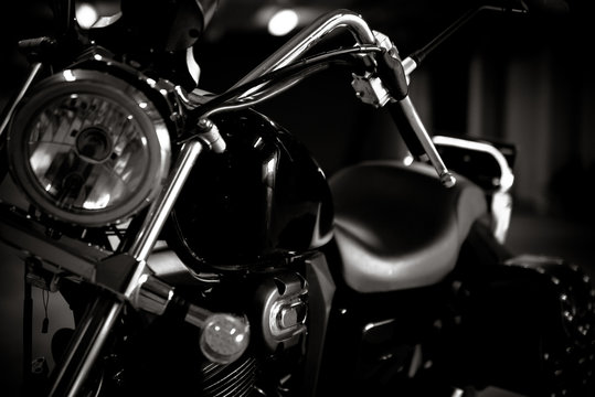 Black and white vintage photo of chopper bike details, chromed, with soft light and reflections, with side leather bags. Motorcycle wallpaper, background