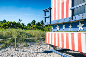Summer beach travel scene with classic red, white, and blue American flag themed lifeguard tower