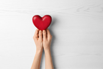 Woman holding decorative heart on white background, top view. Space for text
