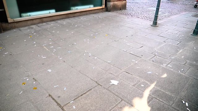 Slow motion of confetti in vortex on the cobblestone asphalt city pavement
