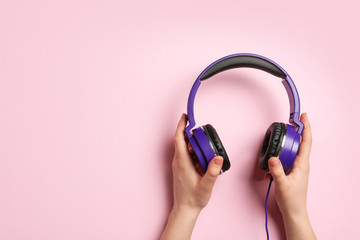 Woman holding stylish headphones on color background, closeup. Space for text