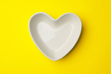 Heart shaped plate on color background, top view