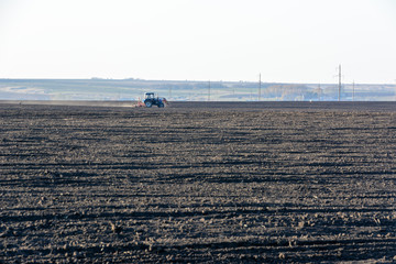 Farm Tractor with plow in a field on a Farm in the sunny day. Farmer in tractor preparing land. It...