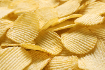 Pile of crispy potato chips as background, closeup