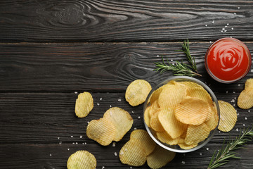 Flat lay composition with potato chips on wooden table. Space for text