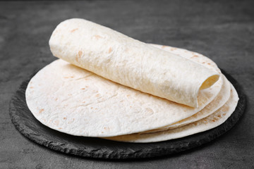 Slate plate with corn tortillas on grey background. Unleavened bread