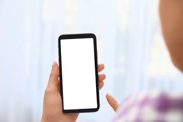 Woman holding smartphone with blank screen on blurred background, closeup of hands. Space for text