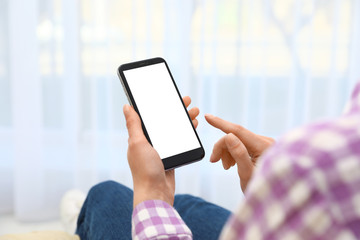 Woman holding smartphone with blank screen indoors, closeup of hands. Space for text