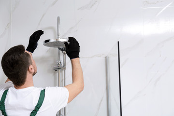Professional handyman working in shower booth indoors, space for text
