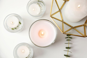 Flat lay composition with burning aromatic candles and eucalyptus on white table