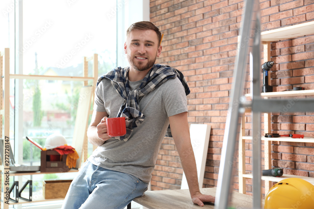 Wall mural Young working man having coffee break indoors