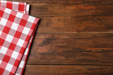 Fototapeta na wymiar Checkered picnic blanket on wooden background, top view. Space for text