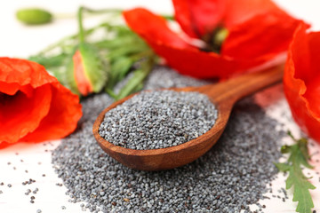 Spoon of poppy seeds and flowers on white table, closeup