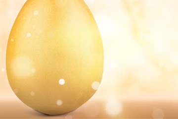 Big golden easter egg on desk with abstract light