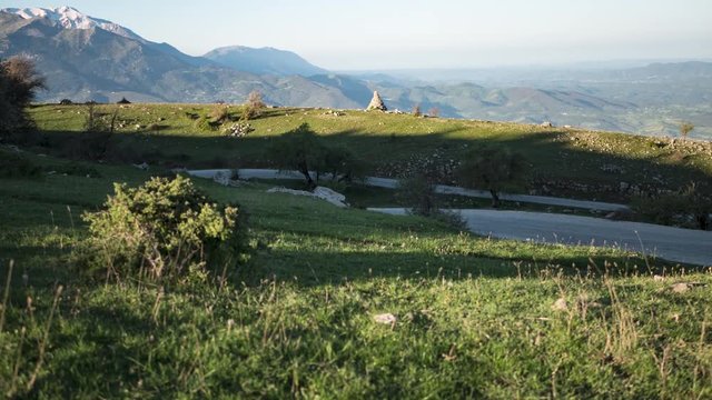 Timelapse on a mountain road. View of high mountains with snow and green grass with the sunlight moving the shadows in the early morning.