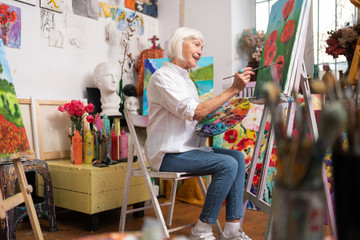 Aged artist feeling truly satisfied while painting red poppies