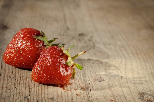 two strawberries on a wooden table