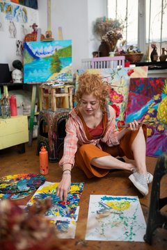 Red-haired woman wearing orange trousers coloring on floor