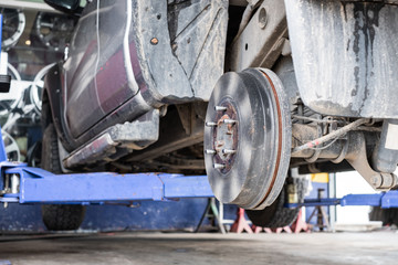 Close up of car disk brake. Car with no wheel on life for repair.