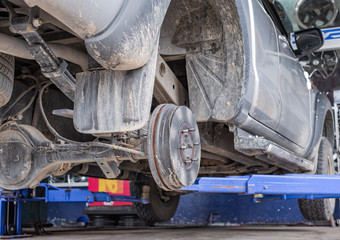 Close up of car disk brake. Car with no wheel on life for repair.