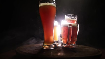 Creative concept. Beer glasses on wooden table at dark toned foggy background. Selective focus
