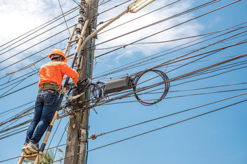 Electrical linemam worker climb a bamboo ladder to repair wire. A telecom engineer installing wire...