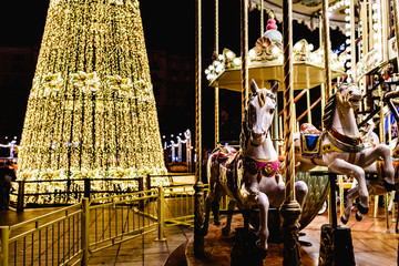 Valencia, Spain - January 2, 2018: Christmas tree illuminated with LED and children's carousel with...