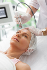 Positive aged woman receiving a beauty procedure
