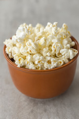 Ceramic bowl with popcorn on gray background