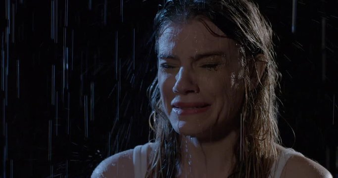 Attractive young woman crying in rain at night. Close up, slow motion 4K recorded at 60fps