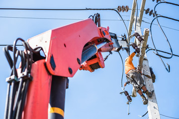 Two electrician workers are climbing on the electric poles to install and repair power lines.