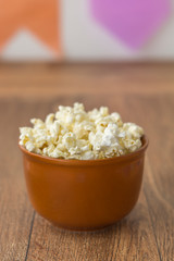 Ceramic bowl with popcorn on gray background