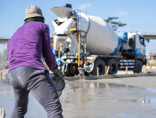 Worker working for leveling concrete pavement for ground flooring at construction site.