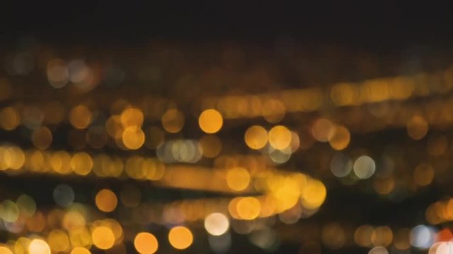 Cinematic shot of city lights defocussed at night. Beautiful bokeh with glimmering colours of orange, blue, white, gold and purple Shot on Canon C100 with L-Series Lenses.