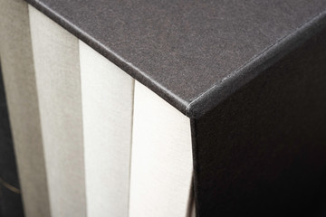 A set of monochromatic cloth-bound books inside an elegant black hard cardboard slipcase and set on a slightly textured and graduated dark background.