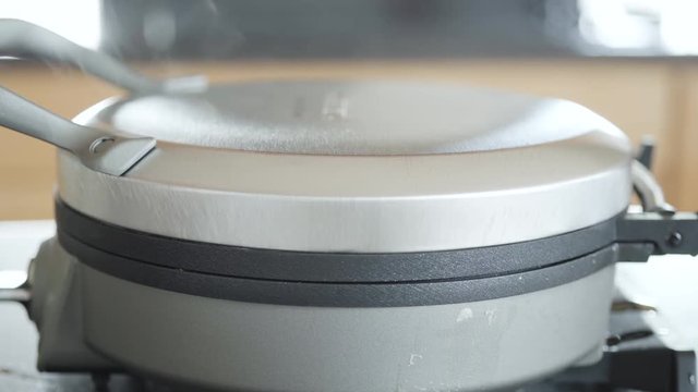 Making homemade waffles in an electric waffle maker.