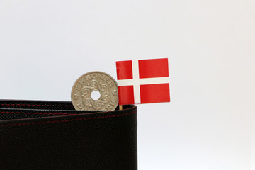 One coin of Danish Kroner money and mini Denmark flag stick on the black wallet with white background.