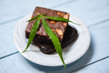 brownies with cannabis leaf marijuana herb on white plate background - cannabis food snack for health