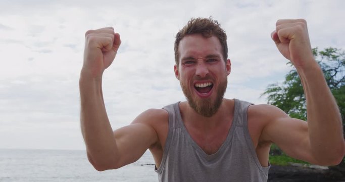 Strong fitness man on beach cheering celebrating flexing arms screaming excited for winning success. Muscular young male athlete flexing arms showing biceps muscles, Sexy caucasian model