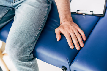 Cropped view of man sitting on couch in medical cabinet