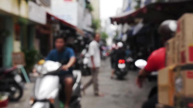 Blurred or bokeh footage of an alley in southeast asia with motorbikes or scooters passing by