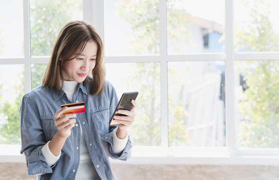 young beautiful woman happily choosing products item from smartphone   and use creadit card to pay for her purchase