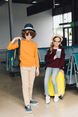 preteen children in sunglasses with baggage and passport in waiting hall