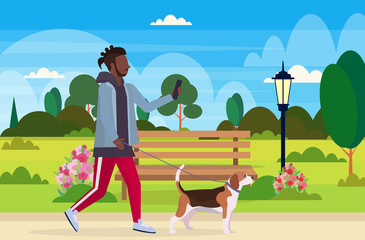 african american man walking with dog using smartphone social media network communication digital gadget addiction concept city urban park landscape background flat full length horizontal