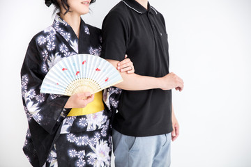 浴衣を着た30代のきれいな女性が白背景で旦那さんと腕を組んでいる