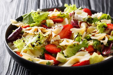 Italian pasta farfalle with avocado, strawberries, lettuce and balsamic sauce close-up on a plate. horizontal