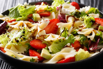 Organic pasta farfalle salad with avocado, strawberries, lettuce, dressed with balsamic sauce close-up. horizontal