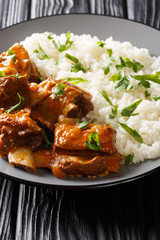 Stewed ribs in a spicy sauce served with white rice close-up. vertical