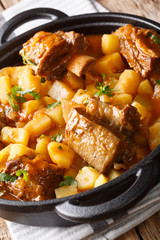 Slowly stewed short beef ribs with potatoes and gravy close-up in a pot. vertical