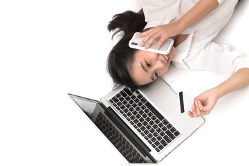 Beautiful woman using her smartphone and  credit card on the web lying on  white background. Shopping online concept.